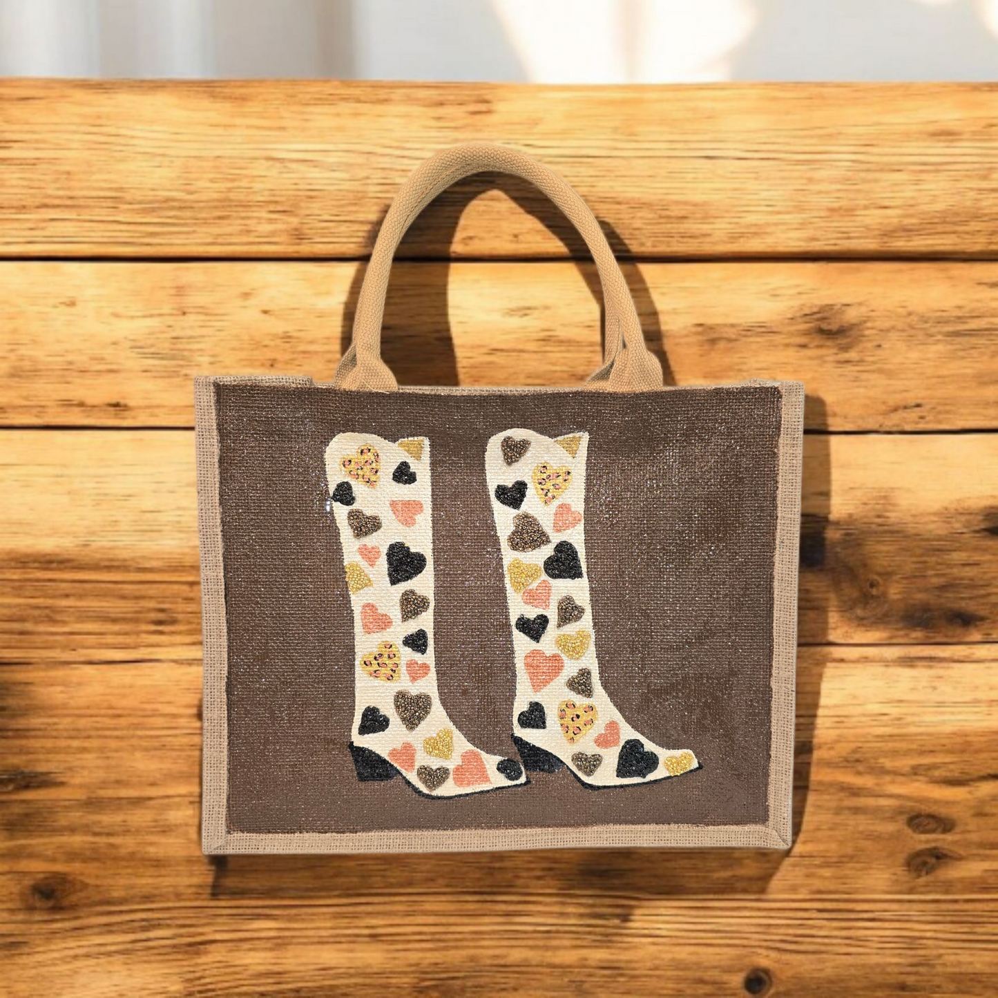 Brown jute tote bag with hand-painted cowboy boots decorated in metallic-colored hearts, accented with beads.