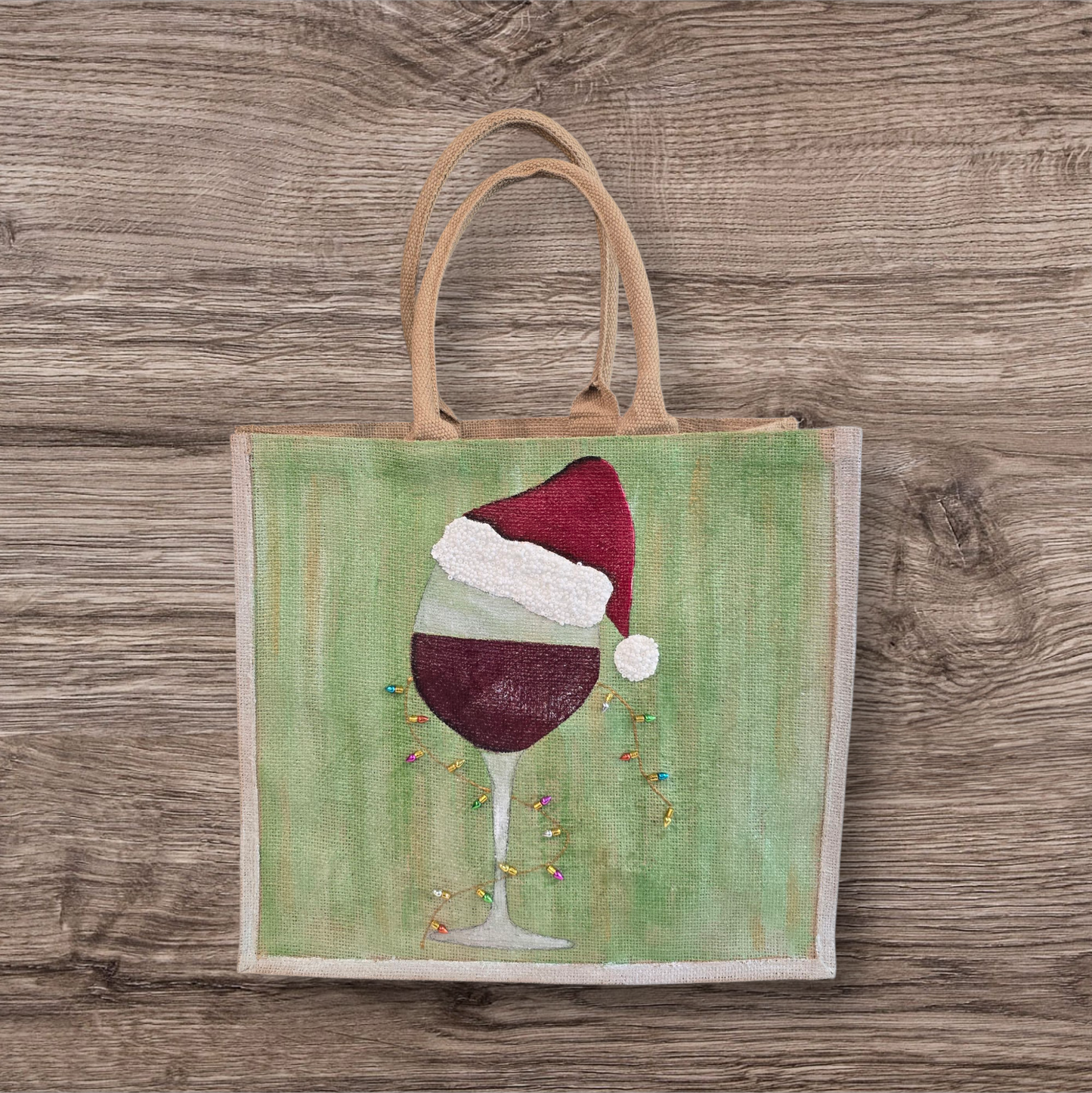 Hand-painted jute tote with a wine glass wearing a Santa hat and tiny holiday lights.