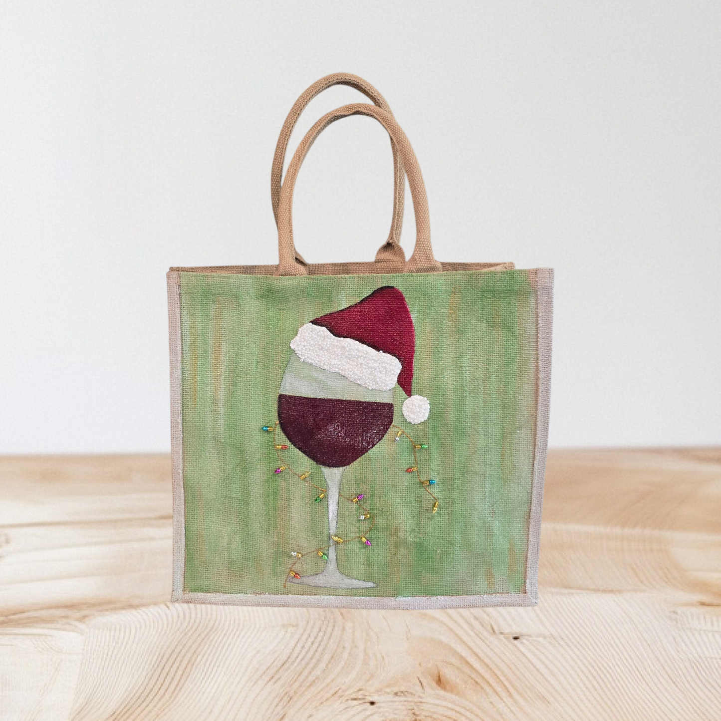 Hand-painted jute tote with a wine glass wearing a Santa hat and tiny holiday lights.
