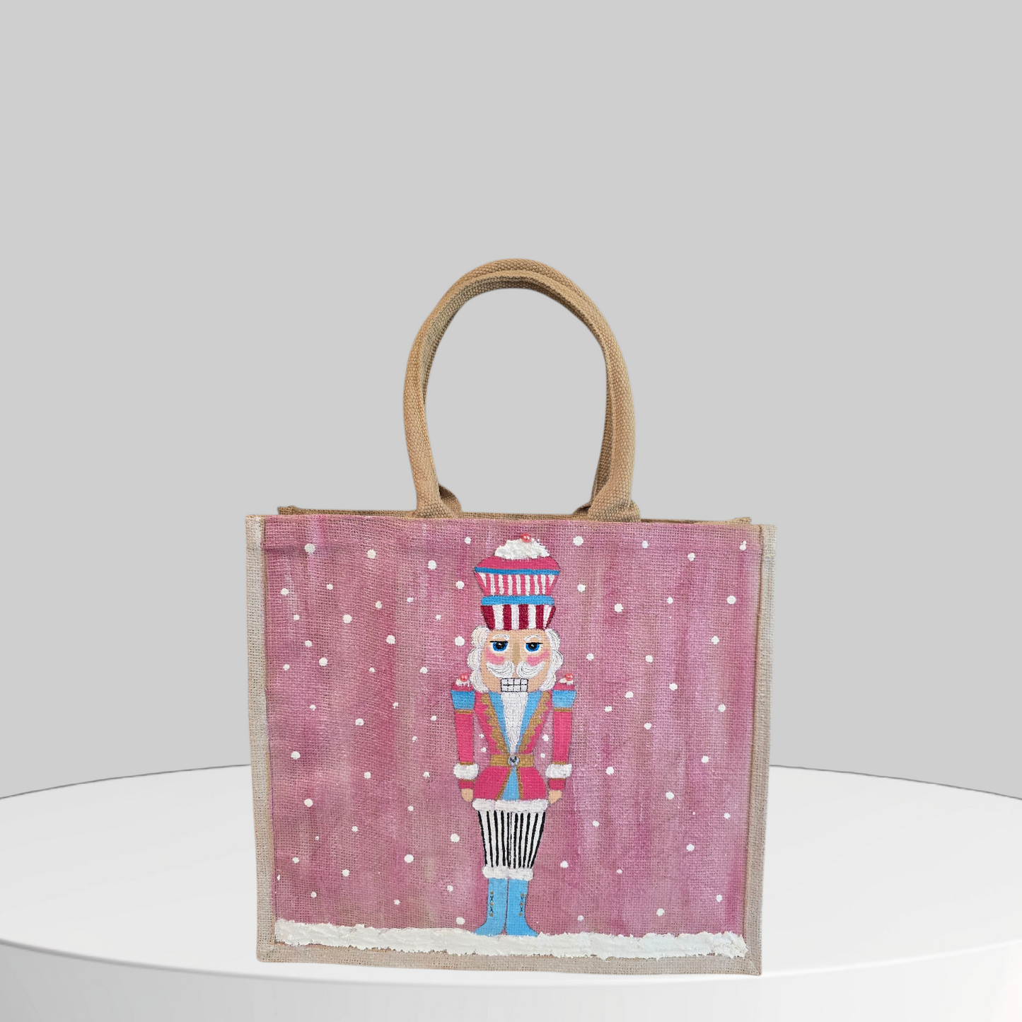 Hand-painted pink Nutcracker on a snowy background, on a jute tote bag.