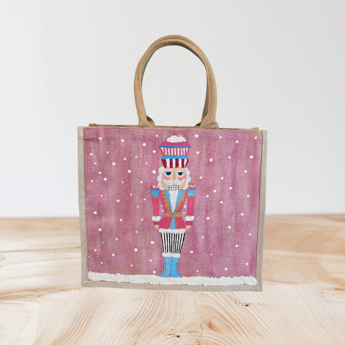 Hand-painted pink Nutcracker on a snowy background, on a jute tote bag.