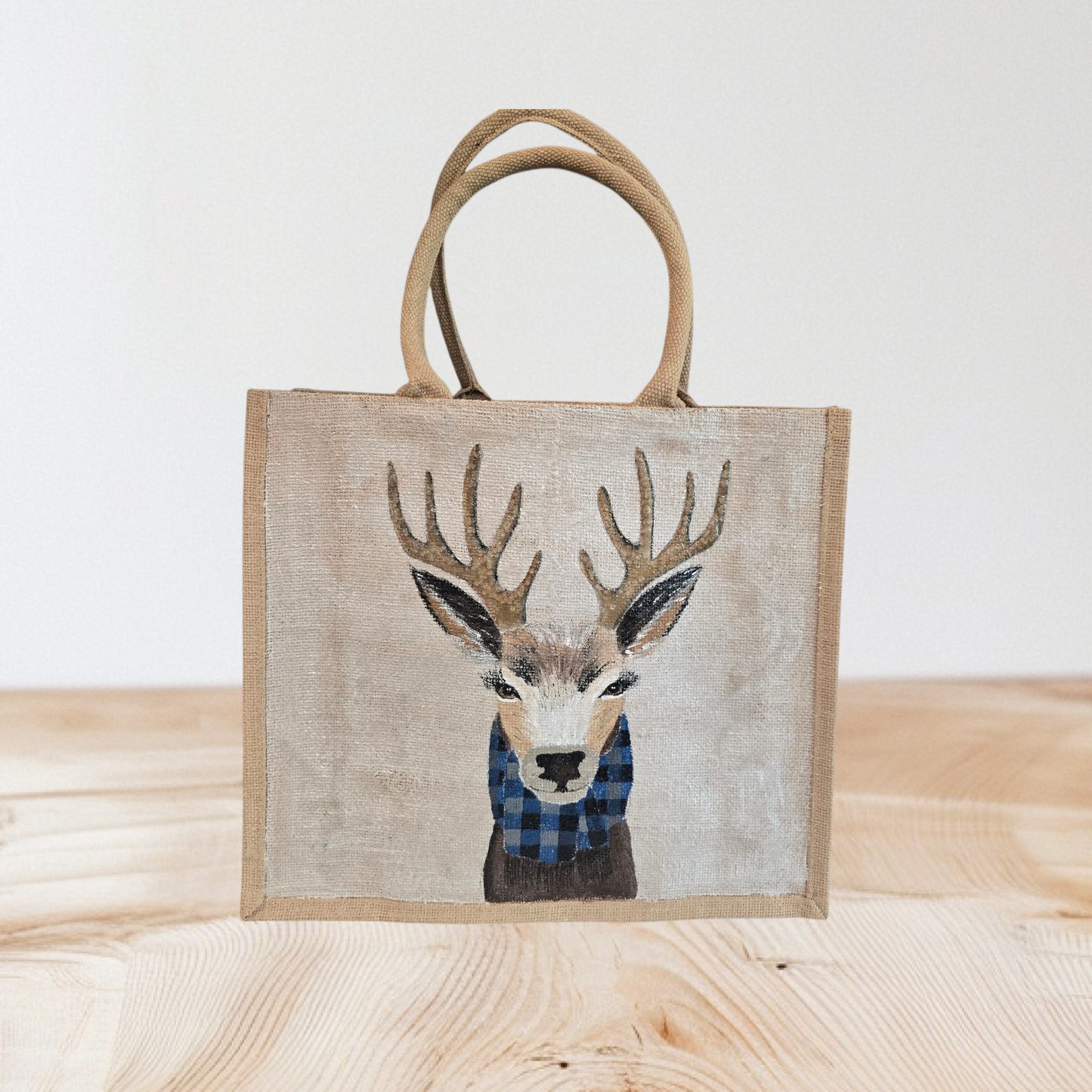 Hand-painted jute tote featuring a reindeer wearing a blue buffalo-plaid scarf.