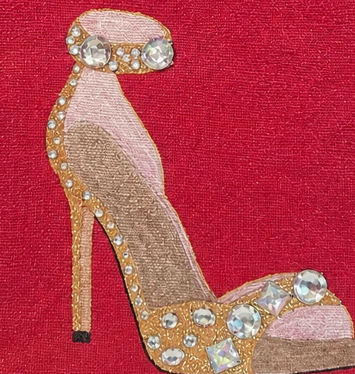 close up of Hand-painted jeweled stiletto tote bag featuring a glamorous gold and blush high heel embellished with sparkling rhinestones on a rich red background. Elegant wearable art handbag with structured jute handles and fashion-inspired design.