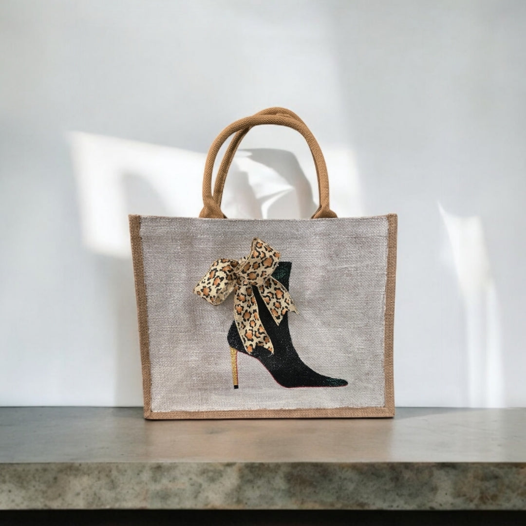 Off white jute tote bag with hand-painted black booties and red soles, featuring beaded embellishments.