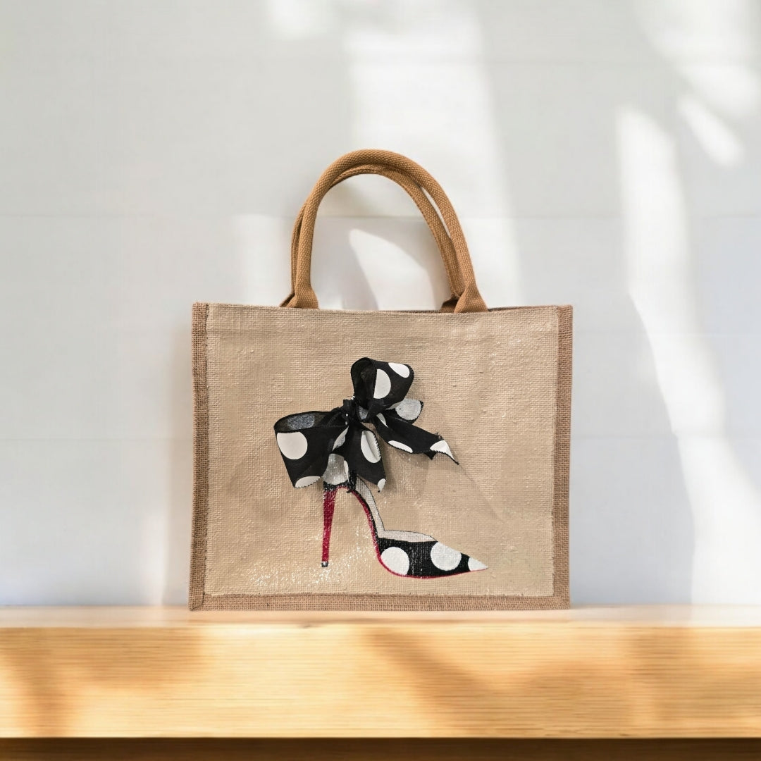 Off white jute tote bag with hand-painted black stilettos, white polka dots, red soles, and beaded accents.