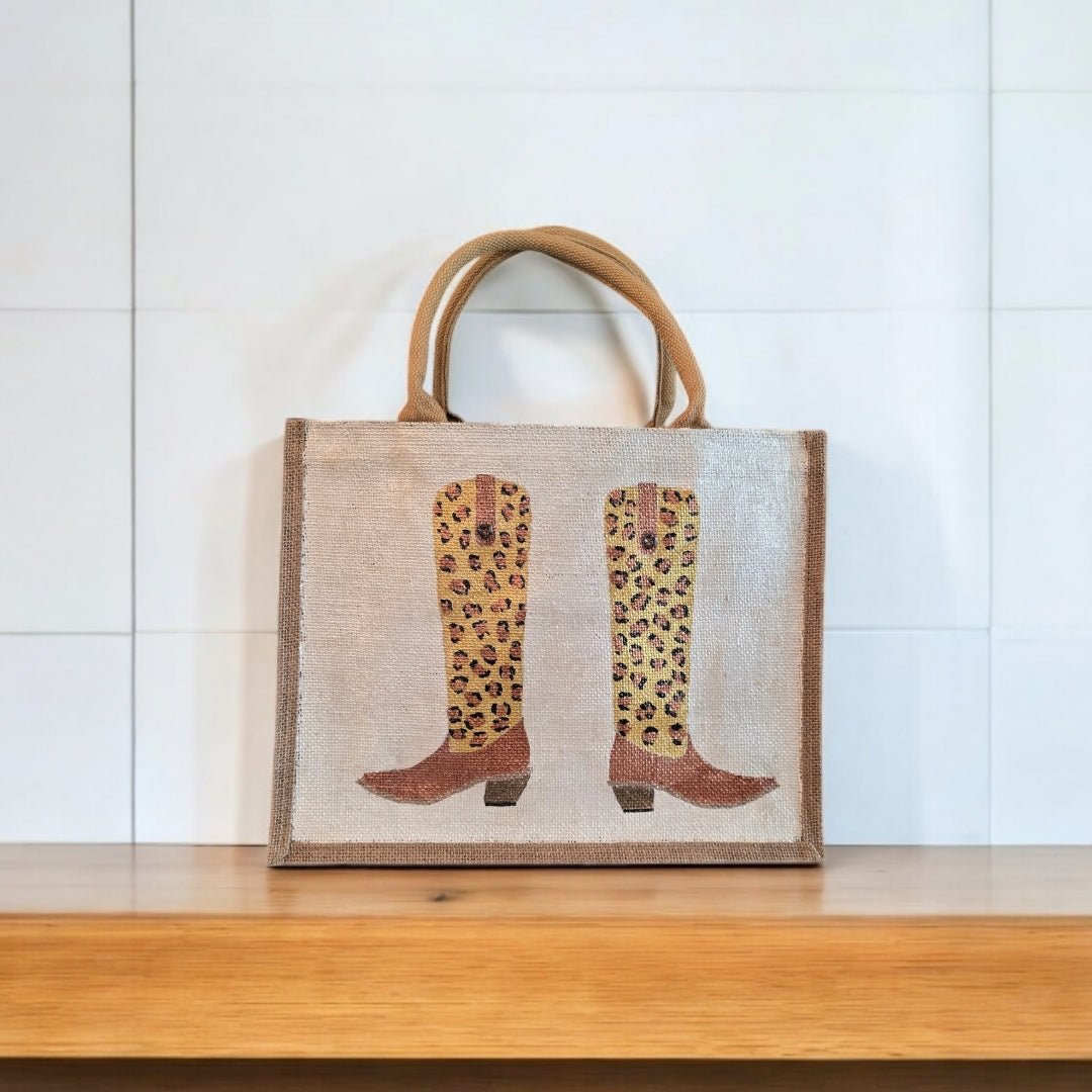 Off white jute tote bag with hand-painted leopard print cowboy boots, detailed with bead accents.