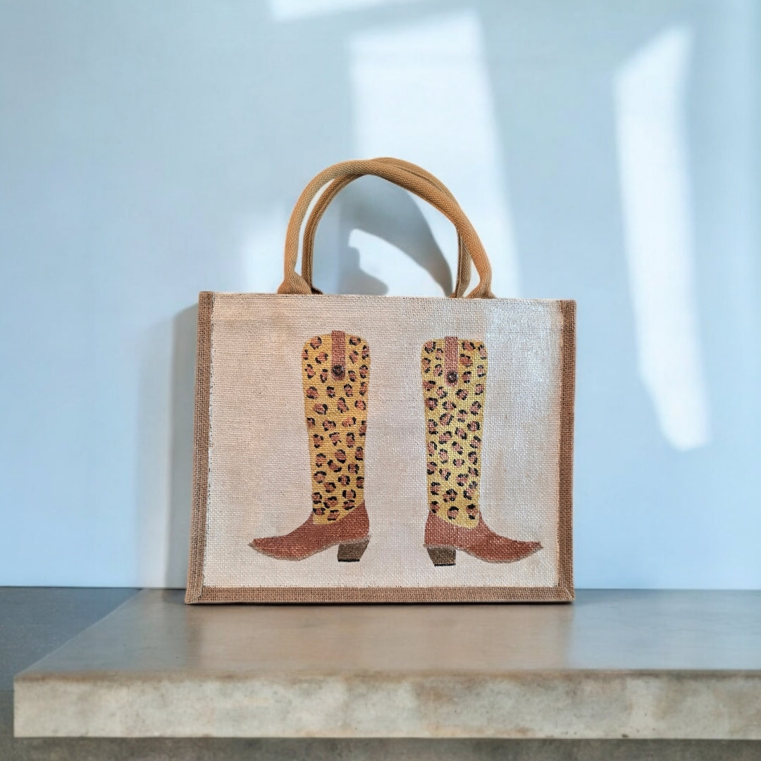 Off white jute tote bag with hand-painted leopard print cowboy boots, detailed with bead accents.