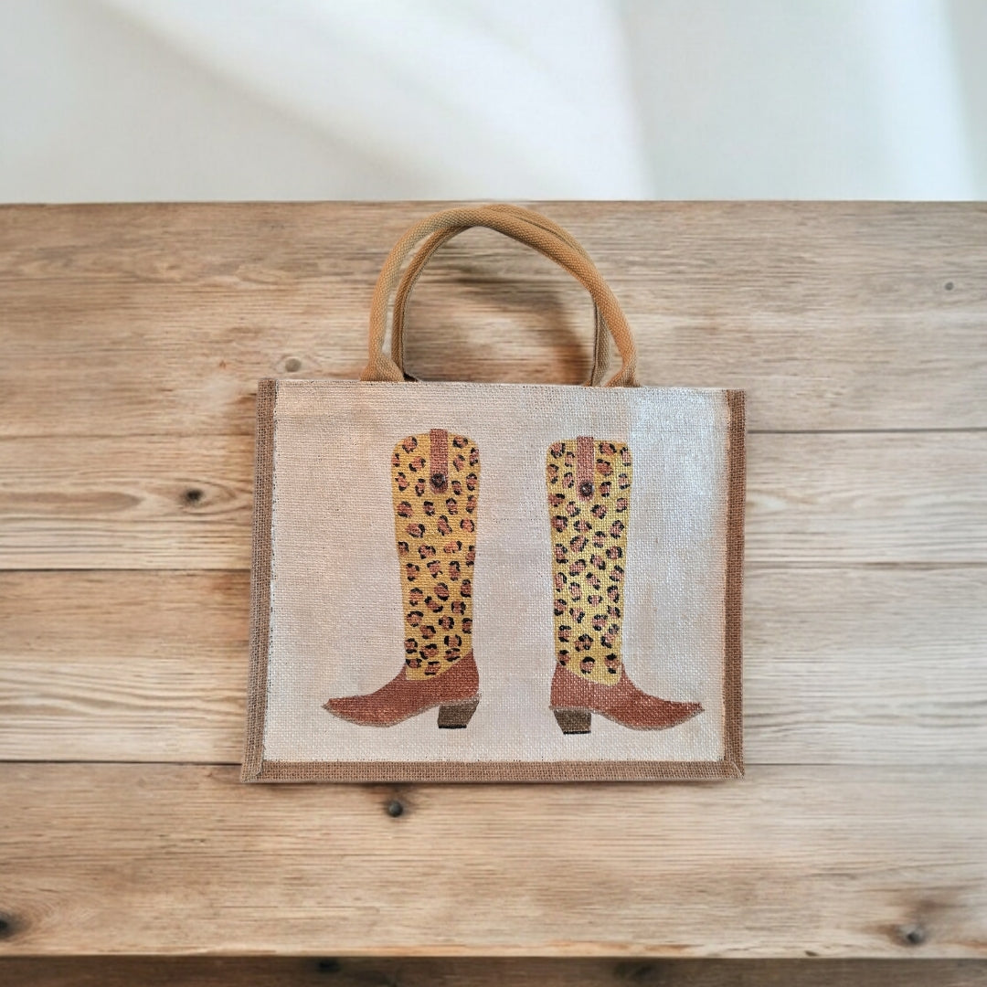 Off white jute tote bag with hand-painted leopard print cowboy boots, detailed with bead accents.