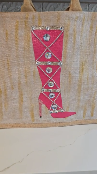 video of Hand-painted pink rhinestone boot tote bag on natural jute background