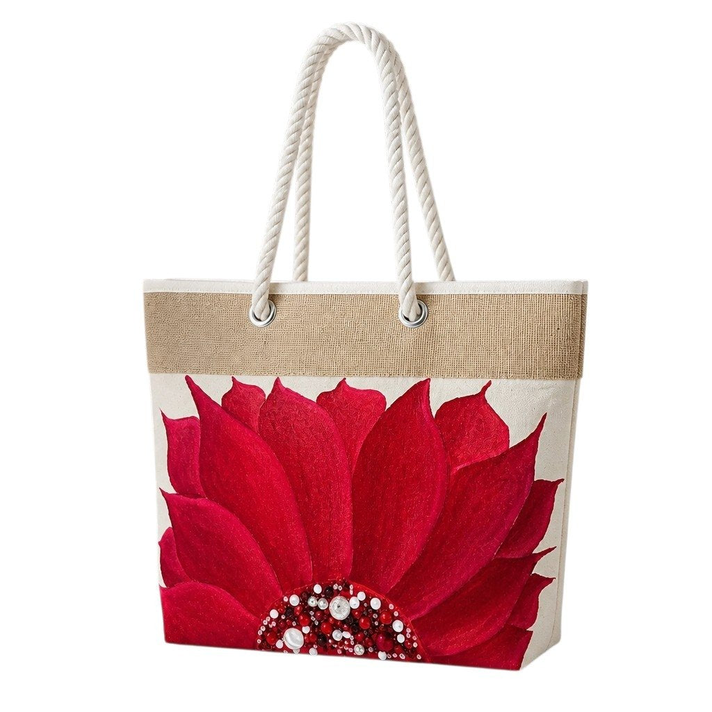 Hand-painted rope handle beach tote featuring a bold red floral design with jeweled embellishments at the flower center, accented with natural jute trim and oversized white rope handles against a neutral background.