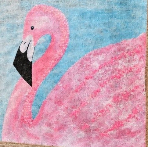 close up of Hand-painted flamingo tote bag on natural jute canvas featuring a large pink flamingo against a soft blue background, finished with sturdy double handles and a structured rectangular silhouette.