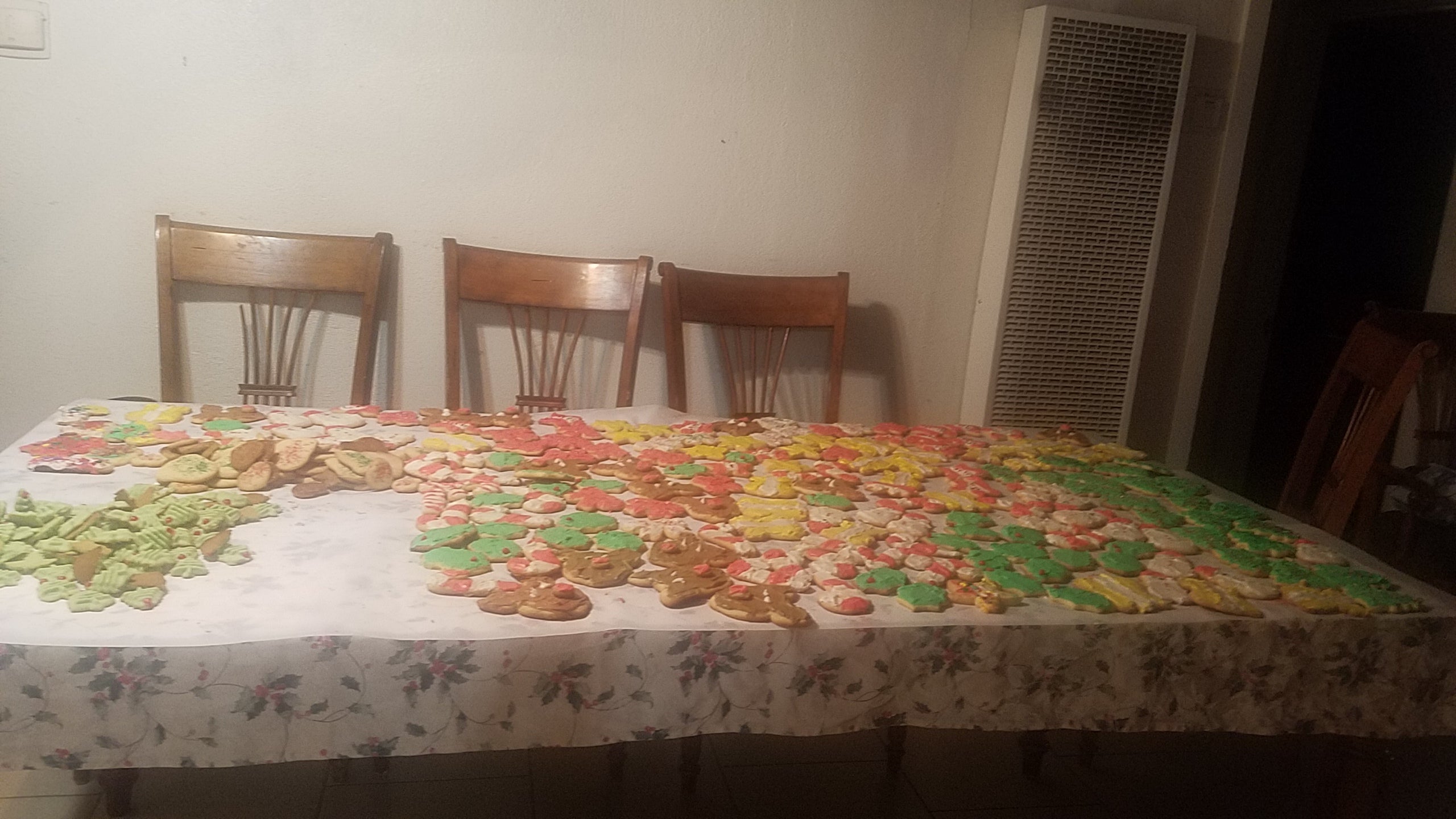 Large table covered with hundreds of decorated Christmas cookies in various colors and shapes.