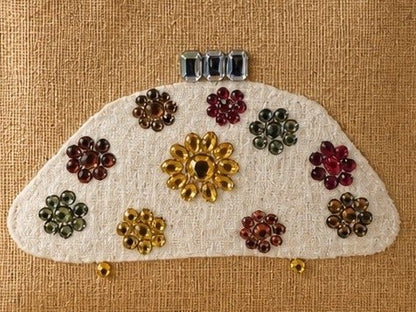 close up of Hand-painted natural jute tote bag featuring a white half-moon purse design embellished with colorful jewel-like floral accents in gold, red, green, and amber tones. The structured tote has rounded woven handles and a neutral background, giving it an elegant artisan-inspired look.