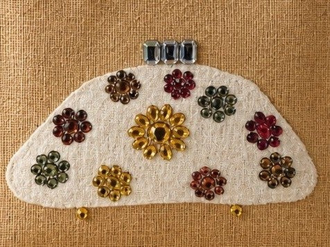 close up of Hand-painted natural jute tote bag featuring a white half-moon purse design embellished with colorful jewel-like floral accents in gold, red, green, and amber tones. The structured tote has rounded woven handles and a neutral background, giving it an elegant artisan-inspired look.