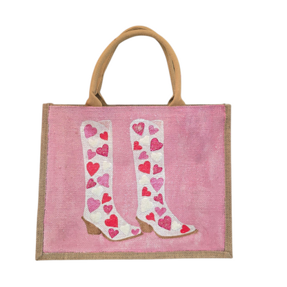 Pink jute tote bag with hand-painted cowboy boots decorated in pink and white hearts, detailed with bead accents.