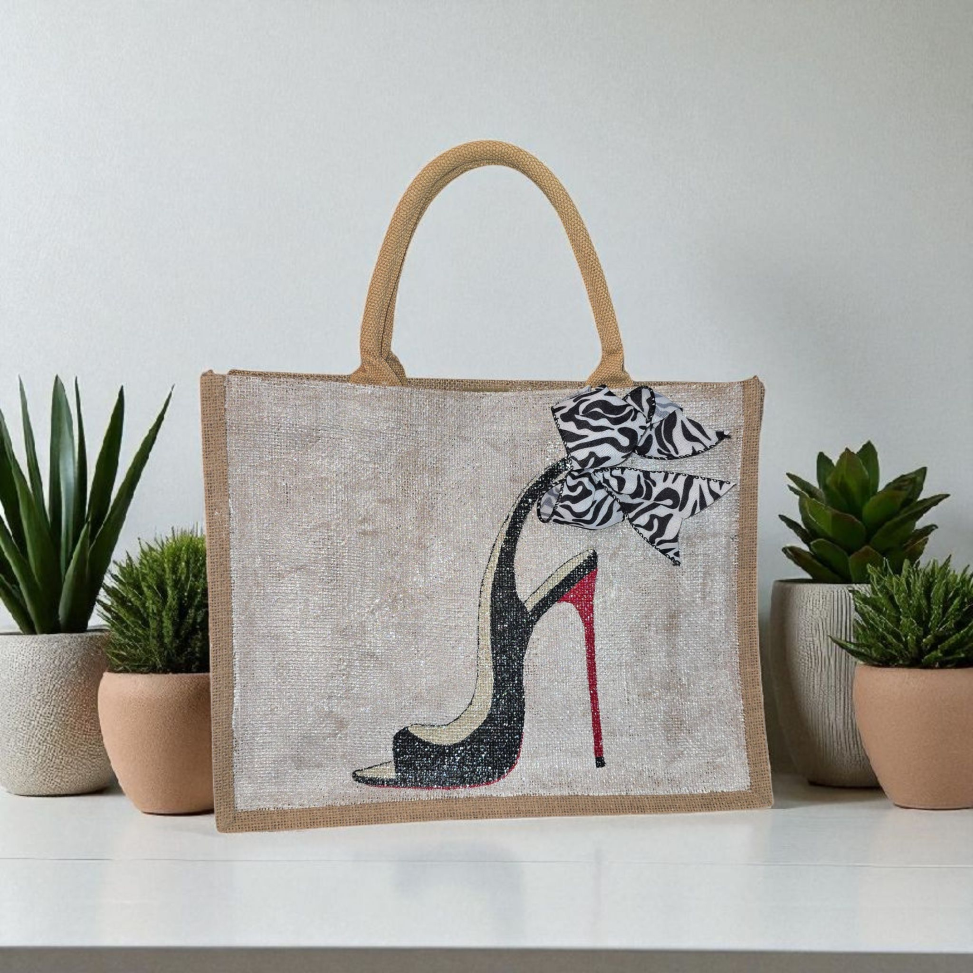 Hand-painted jute tote bag featuring a black stiletto heel with red sole and a zebra-print bow, designed by Dana’s Uncommon Glass