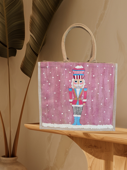 Hand-painted pink Nutcracker on a snowy background, on a jute tote bag.