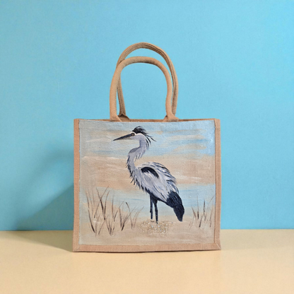 hand painted blue heron with a beachy background embellished with glitter glass on jute tote