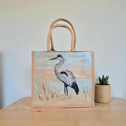 hand painted blue heron with a beachy background embellished with glitter glass on jute tote