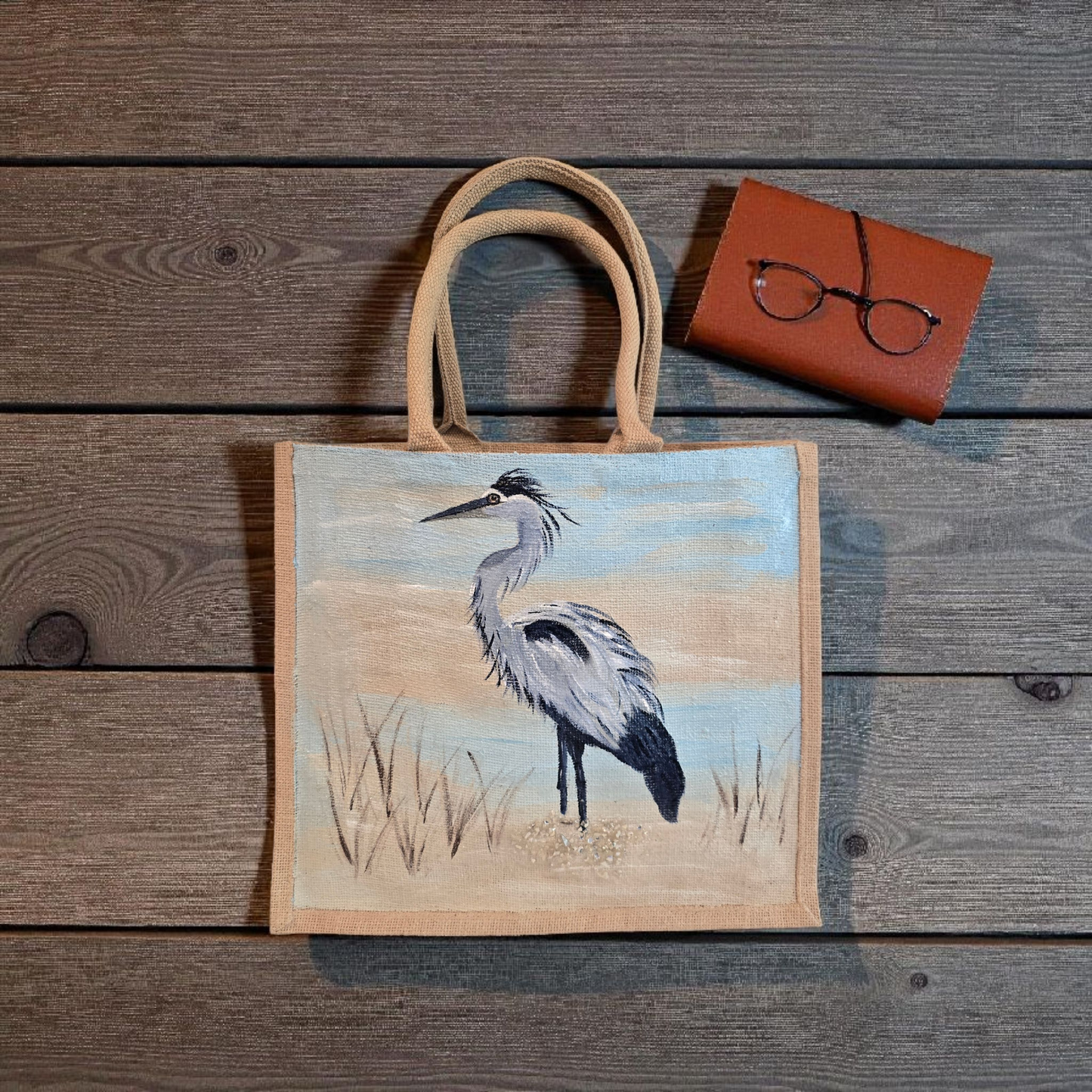 hand painted blue heron with a beachy background embellished with glitter glass on jute tote