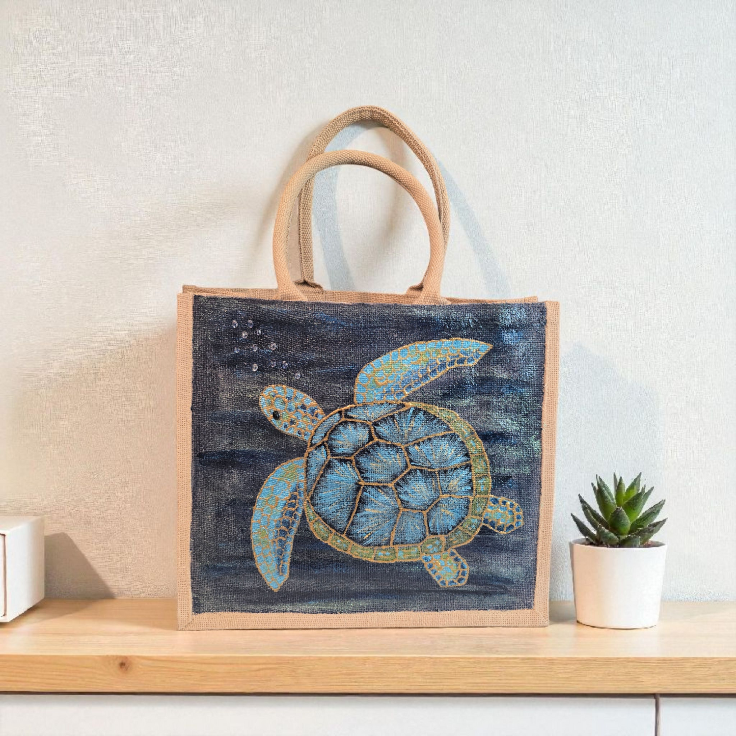 sea turtle hand-painted on burlap jute tote bag in blues, greens and golds on a navy metallic background.