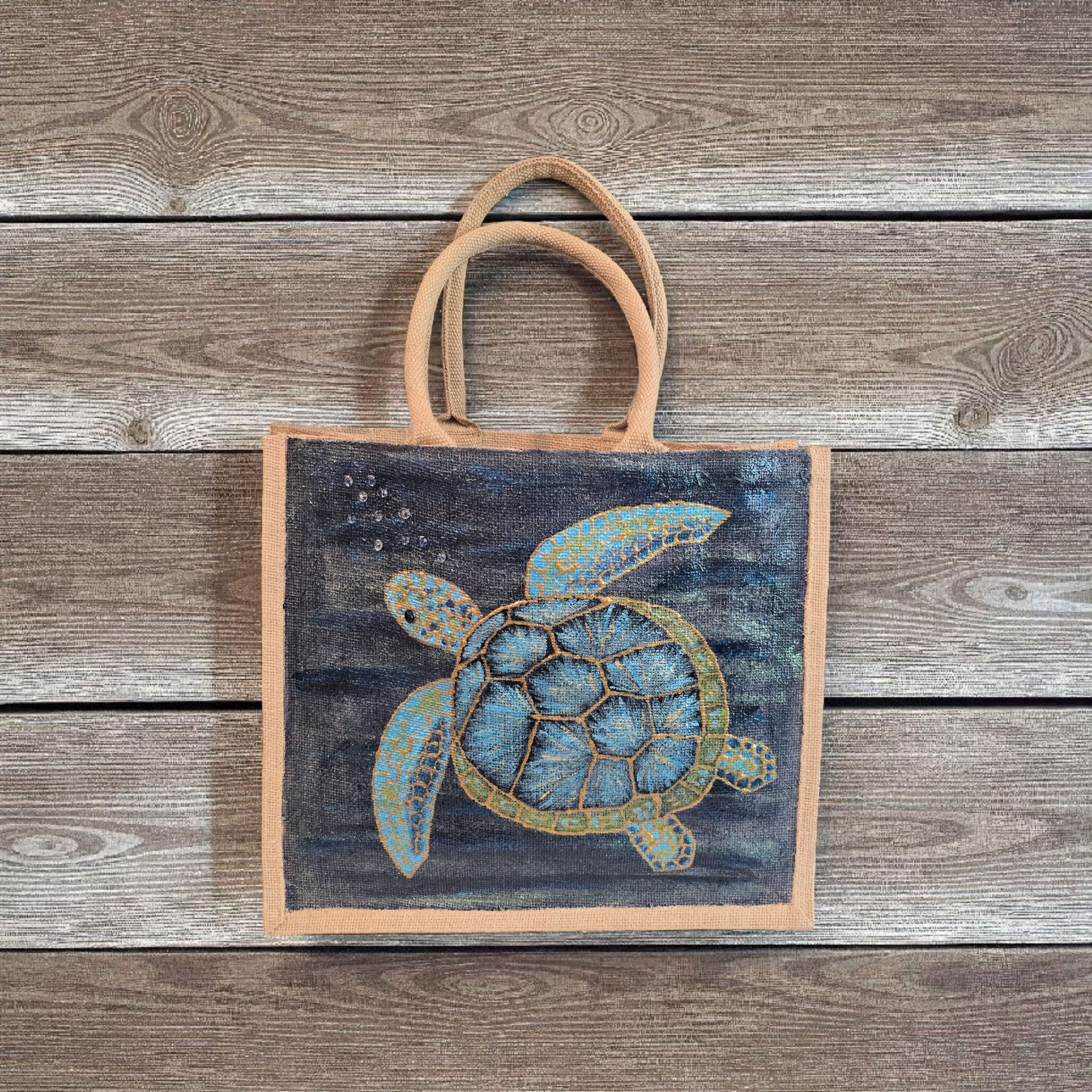 sea turtle hand-painted on burlap jute tote bag in blues, greens and golds on a navy metallic background.