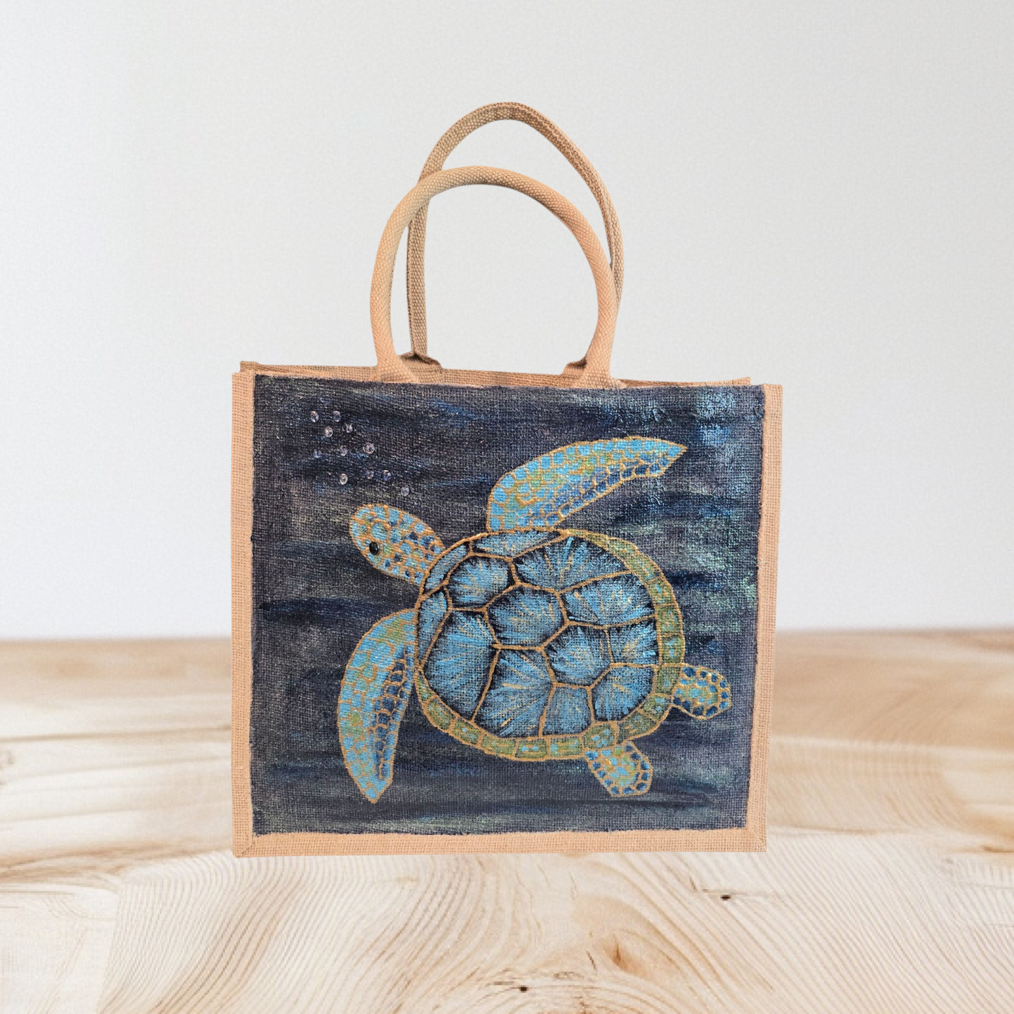 sea turtle hand-painted on burlap jute tote bag in blues, greens and golds on a navy metallic background.