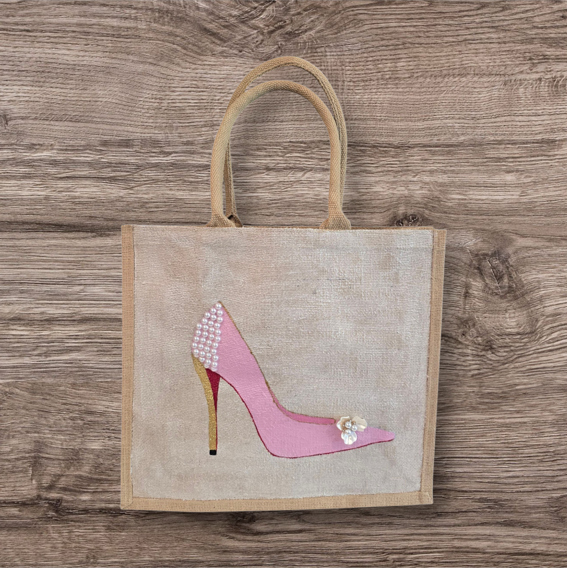 Pink Stiletto hand painted on jute tote bag embellished with jewels and pearls on an off white metallic background.