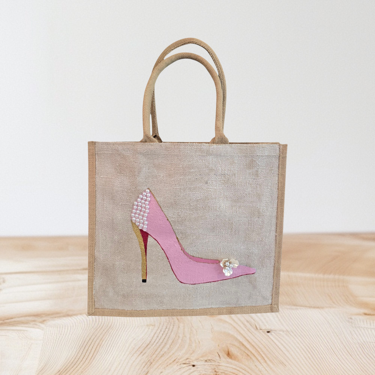 Pink Stiletto hand painted on jute tote bag embellished with jewels and pearls on an off white metallic background.