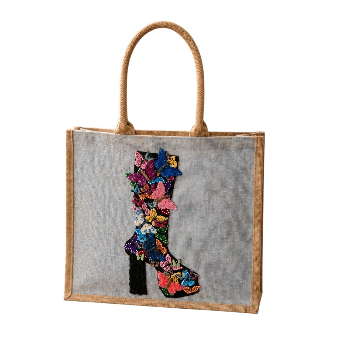 Hand-painted butterfly boot tote bag on soft blue jute canvas featuring a colorful floral and butterfly western boot design, photographed in a neutral boutique-inspired setting with modern styling accents.