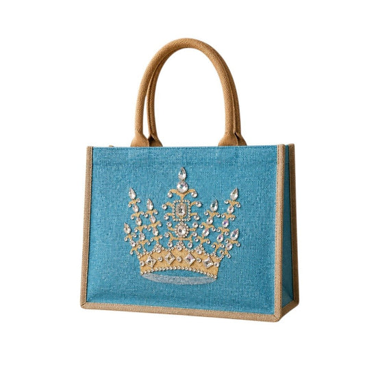 Hand-painted turquoise jute tote bag featuring a jeweled gold crown design embellished with sparkling rhinestones and pearls, finished with natural burlap trim and rounded handles.