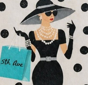 close up of Hand-painted jute tote bag featuring a stylish woman in a black dress and wide-brim hat with pearl jewelry, black polka dot background, and turquoise “5th Ave” shopping bag detail.
