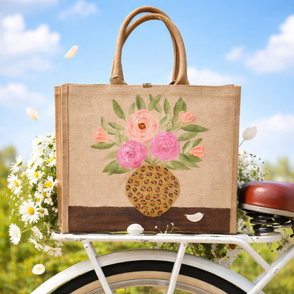 Hand-painted jute tote bag featuring pink and peach flowers arranged in a leopard print vase on a natural canvas background