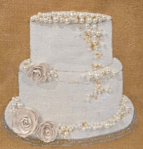 close up of Hand-painted jute tote bag featuring an embellished three-tier white wedding cake design with pearl accents, floral details, and shimmering trim on a rich gold background.