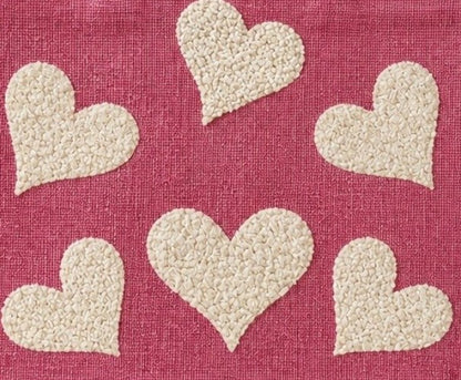 close up of Hand-painted pink jute shopper bag featuring five textured cream hearts on a bright pink background with natural tan handles and trim.