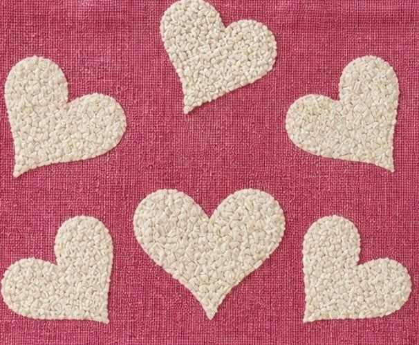 close up of Hand-painted pink jute shopper bag featuring five textured cream hearts on a bright pink background with natural tan handles and trim.