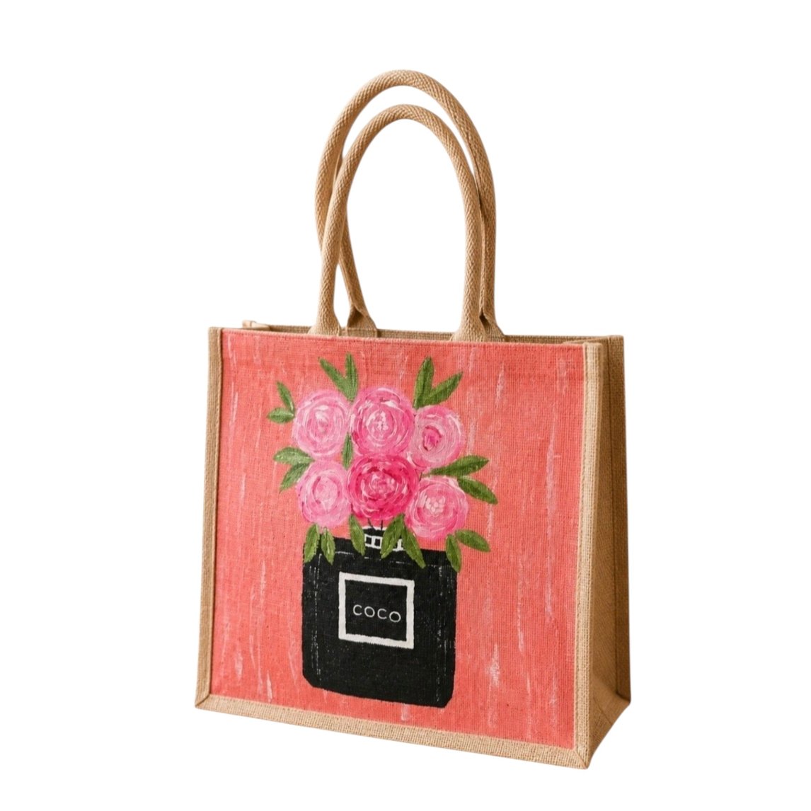 Hand-painted jute tote bag featuring a coral pink background with a black perfume bottle vase filled with pink floral blooms and green leaves. The structured tote has natural woven handles and a feminine, fashion-inspired design with playful boutique-style charm.