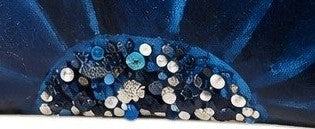 close up of Hand-painted rope handle beach tote featuring a bold navy blue floral design with sparkling jeweled embellishments at the flower center, accented with natural jute trim and oversized cream rope handles against a neutral background.