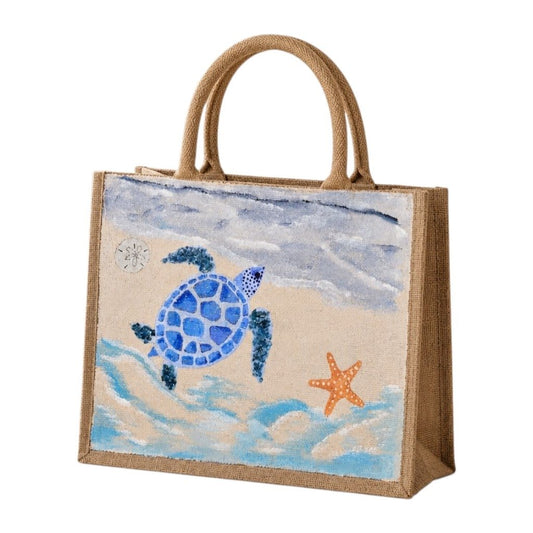 Hand-painted jute tote bag featuring a blue sea turtle swimming through ocean waves with a starfish and soft coastal sky background. Beach-inspired artisan tote with natural rope handles and calming seaside colors.