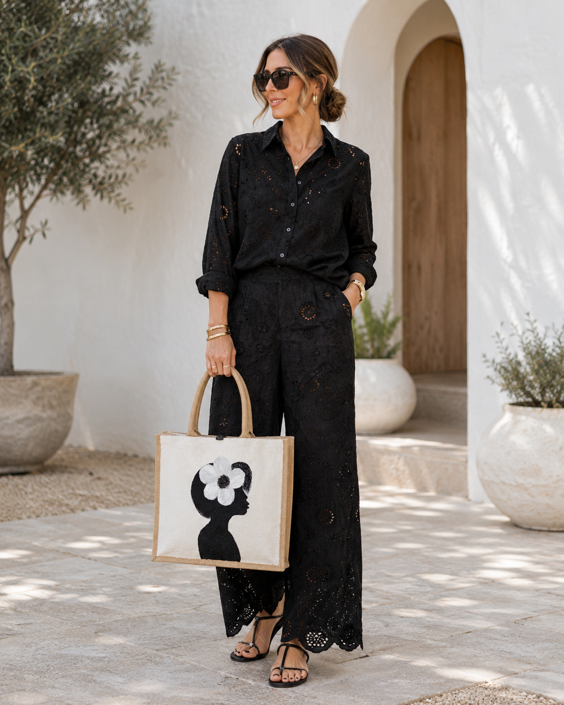 woman holding Hand-painted jute tote bag featuring a minimalist black silhouette of a woman in profile with a bold white flower in her hair on a pearl white background. This chic neutral tote includes natural jute handles, a magnetic closure, and modern wearable art styling.