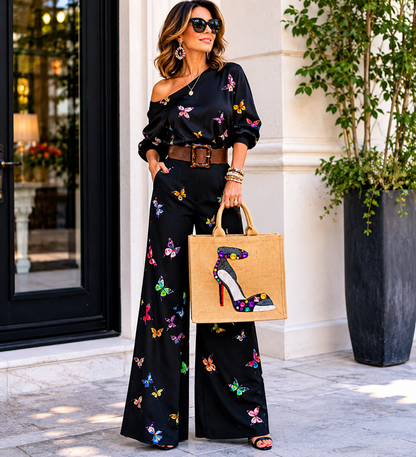 woman holding Hand-painted jute shopper tote featuring a jeweled black stiletto shoe embellished with colorful gems and rhinestones, designed as bold wearable fashion art.