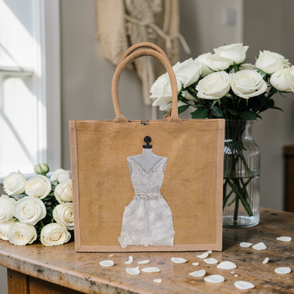 Hand-painted jute tote bag featuring an elegant white bridal dress with shimmering details on a natural canvas background