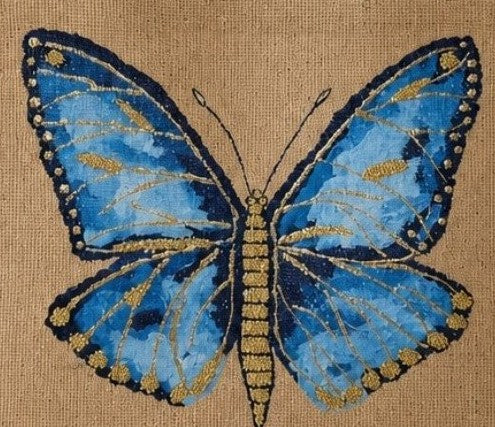 Close up of Hand-painted butterfly tote bag on natural jute canvas featuring a vibrant blue butterfly with navy and gold detailing, accented with delicate gold highlights and intricate wing patterns.