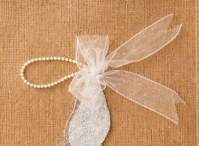 close up of a hand-painted jute tote bag featuring a white glitter stiletto shoe with pearl and ribbon embellishments.