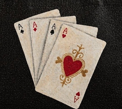 close up of Hand-painted black jute tote bag featuring four aces playing cards with a red heart design, framed by natural burlap trim and rounded handles.