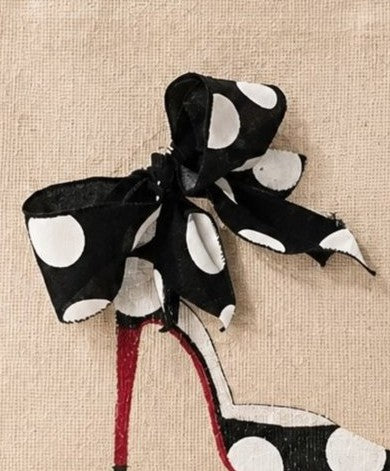 close up of Hand-painted jute tote bag featuring a black-and-white polka dot stiletto shoe with a red sole and oversized black ribbon bow, accented with large white polka dots on a natural canvas background.