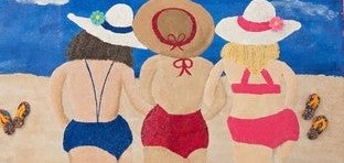Hand-painted pink fringed tote bag featuring three women walking into the ocean in colorful swimsuits and sun hats, with a beach scene, blue sky, clouds, and flip-flop details on a vibrant coastal-inspired design.