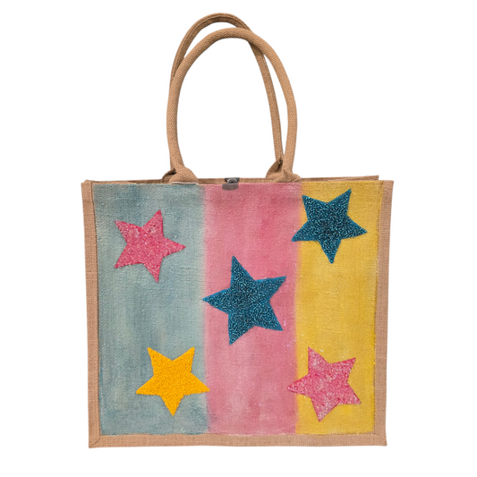 Hand-painted jute tote bag with colorful vertical stripes in blue, pink, and yellow, featuring textured glitter stars in bright colors
