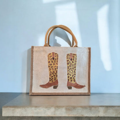 Off white jute tote bag with hand-painted leopard print cowboy boots, detailed with bead accents.