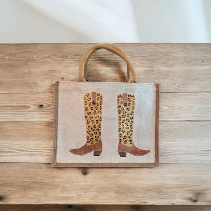 Off white jute tote bag with hand-painted leopard print cowboy boots, detailed with bead accents.